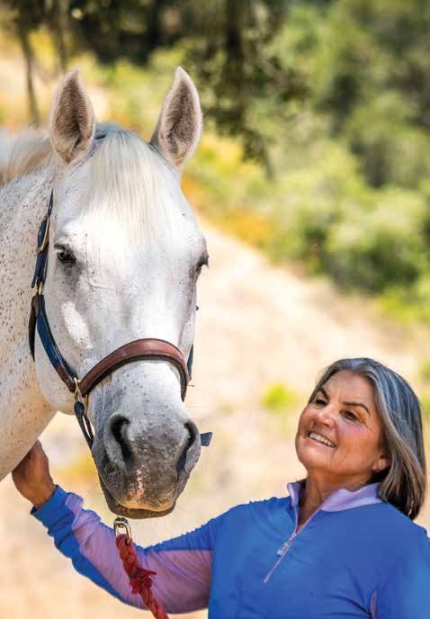Anita Parra standing beside Sterling, her gray horse, one hand on his face.